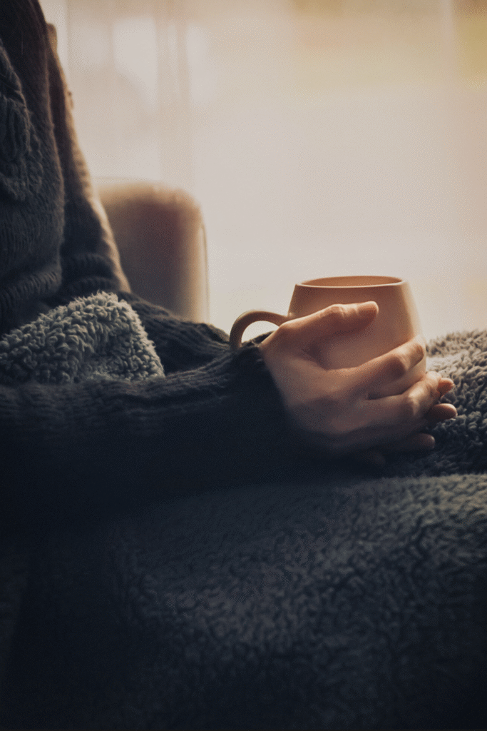 Holding a cup of hot tea relaxing in a calm and warm room.